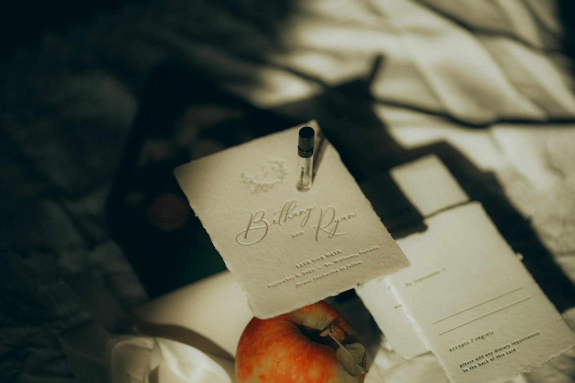 Eleganckie zaproszenie save the date na jasnym tle z jabłkiem i perfumami