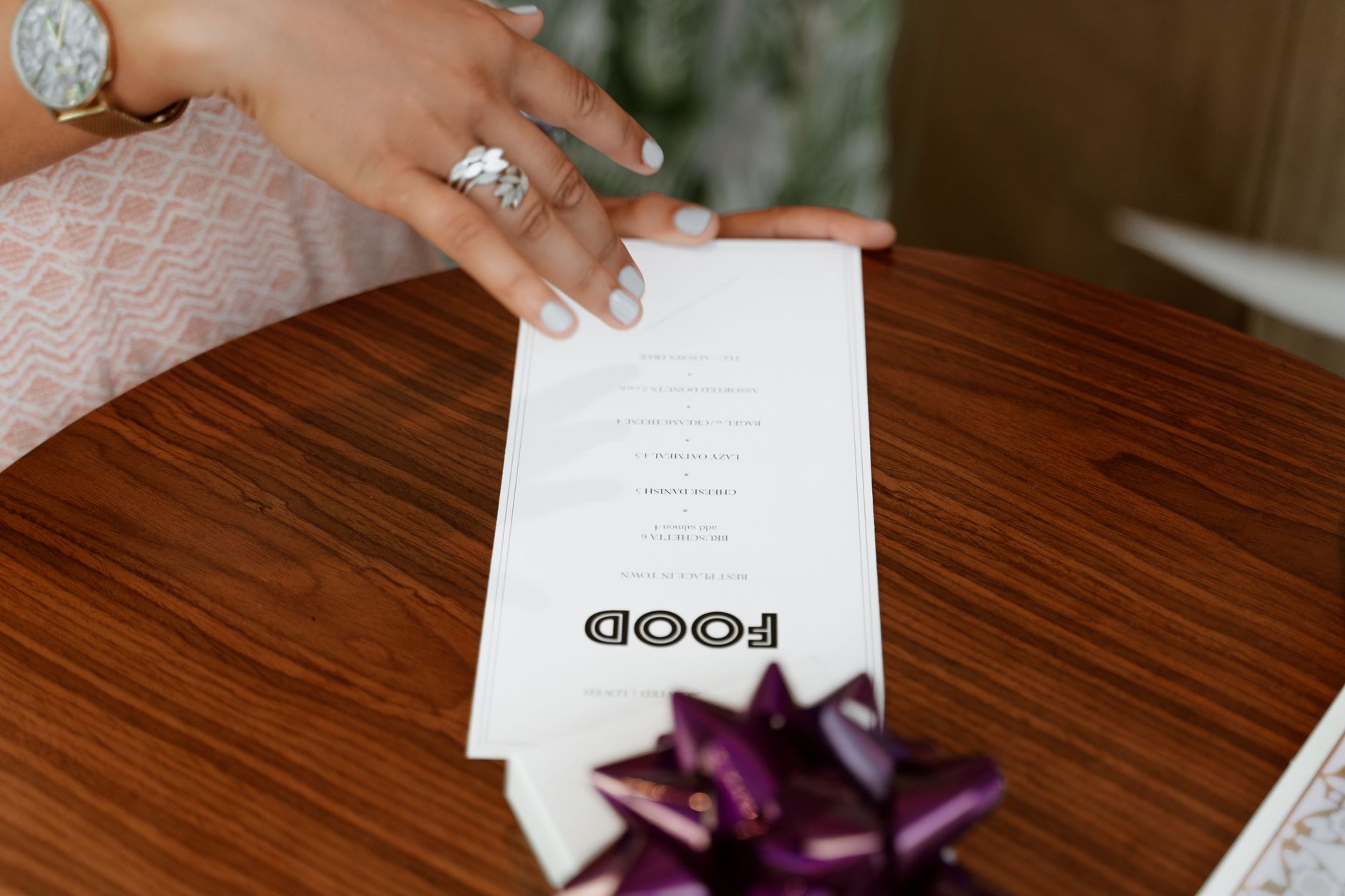 Dłoń trzymająca eleganckie menu nad drewnianym stołem w restauracji